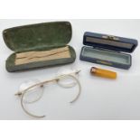 An Edwardian gold rimmed amber cheroot holder together with a pair spectacles with 12ct gold arms