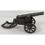 A cast metal model of a cannon, with moving wheels and removable barrel. Approx. 11cm tall x 23cm