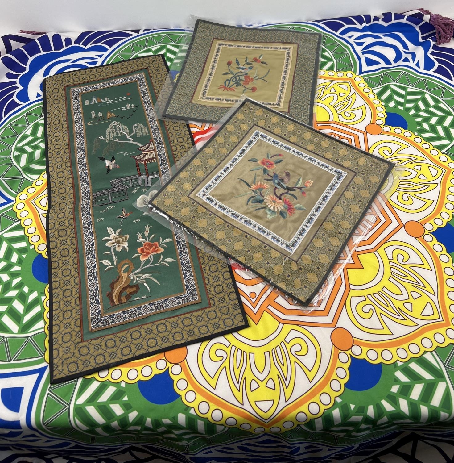 A circular fringed brightly coloured Mandala style tablecloth together with 3 embroidered panels.