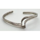 A silver wave design torque style bangle. Silver marks to inside. Total weight approx 13.1g.
