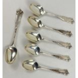 A set of 6 Edwardian silver teaspoons with ornately shaped handles and decorative embossed design.
