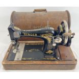 An antique wooden cased Singer sewing machine, black with gold floral decoration and shuttle bobbin.
