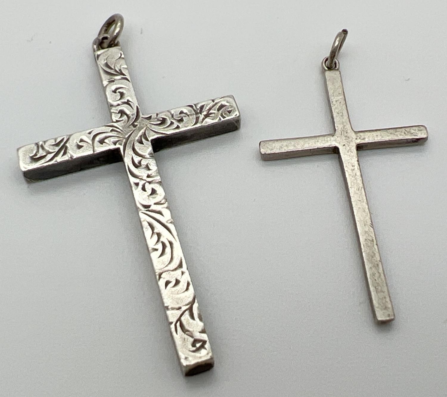 2 silver cross pendants with hanging bales. One plain, the other with engraved decoration to