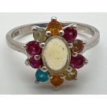 A silver multi stone cluster ring set with oval shaped central opal surrounded by assorted