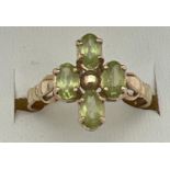 A 9ct gold and peridot ring in a quatrefoil shaped setting with shaped shoulders. 4 oval cut peridot