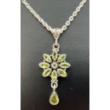 A silver and peridot flower design pendant on an 18" silver belcher chain. Pendant stamped 925 to