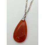 A teardrop shaped orange jade pendant on a silver 18" figaro curb chain. With lobster claw clasp,