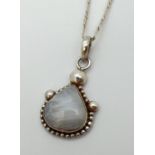 A silver and moonstone pendant, on a 17" silver figaro curb chain with lobster claw clasp. Pendant