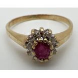 An unmarked 9ct yellow gold, ruby and diamond cluster ring in a high mount. Central oval cut ruby (