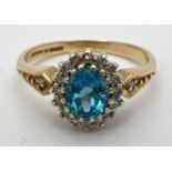 A 9ct gold, London blue topaz and diamond ring in a halo setting. Central oval cut topaz (approx.