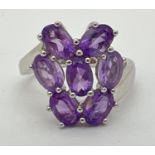 A Genuine Gem Company silver and amethyst large dress ring. Set with 7 oval cut amethysts in a