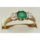 A vintage 18ct gold, emerald and diamond trilogy ring with channelled design to shoulders. Central