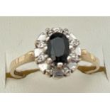 A 9ct gold sapphire and diamond dress ring. Central oval cut sapphire with 4 small diamonds in an