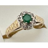 A vintage 9ct gold, emerald and diamond cluster ring with engraved detail to shoulders. Fully