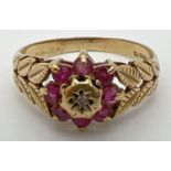 A vintage 9ct gold, ruby and diamond dress ring in a flower shaped setting. Central diamond
