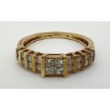 A 10k yellow gold and diamond ring set with 4 central princess cut stones flanked by 8 channel set
