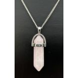 A rose quartz pointed hexagonal pendulum pendant in a white metal setting. On an 18" silver curb