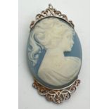 A vintage classic style blue cameo brooch in a decorated pierced work mount. Marked silver to
