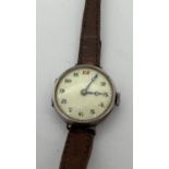 An antique silver cased Swiss 15 jewels wristwatch with brown leather strap. White enamel face