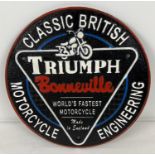 A circular shaped painted cast iron Triumph Bonneville motorcycles wall plaque. In black, red,