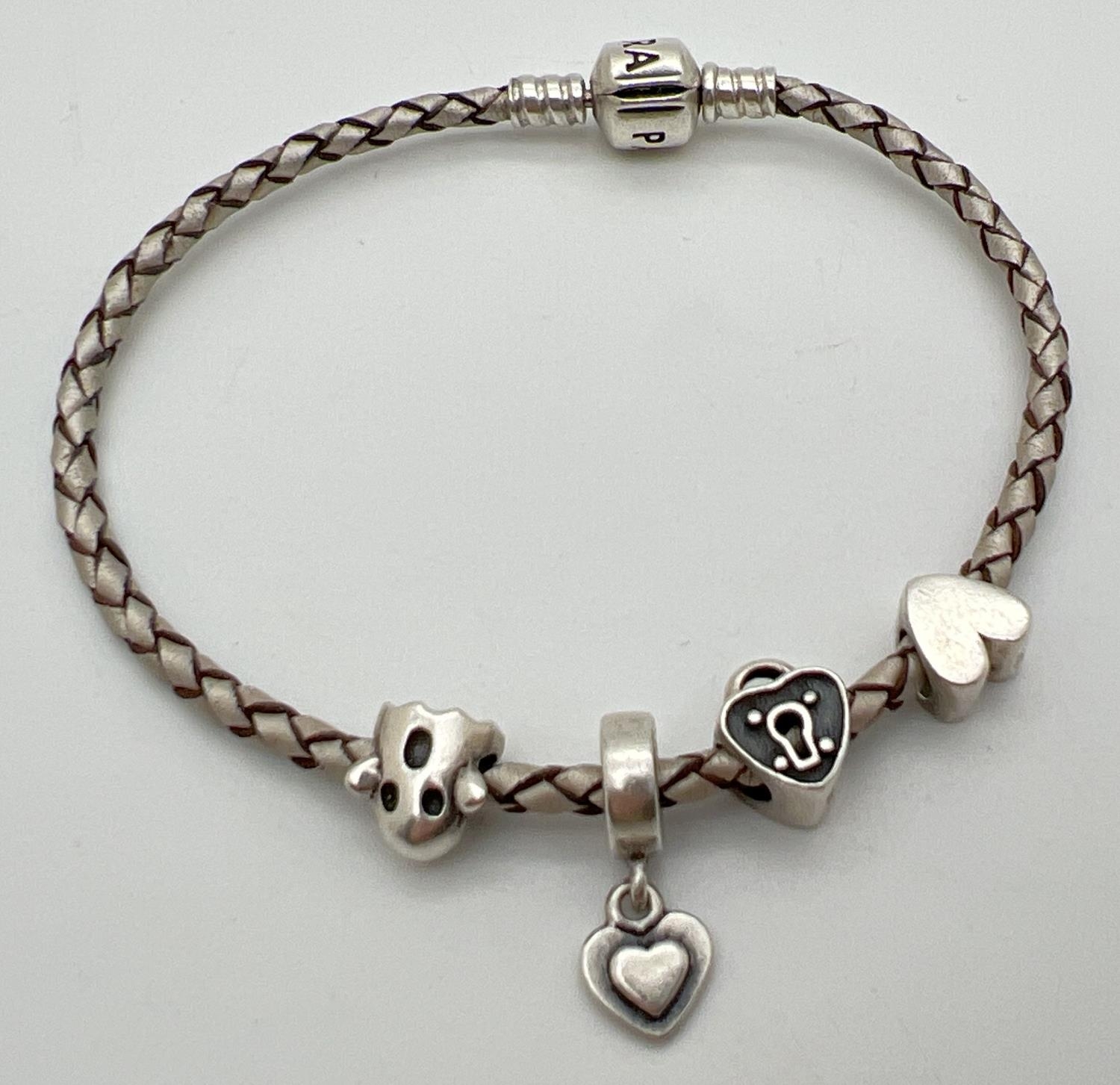 An 8" silver leather plaited charm bracelet by Pandora with 4 charms. Charms comprise: solid