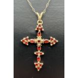 A 9ct gold garnet set cross shaped pendant on a fine 18" belcher chain with spring ring clasp.