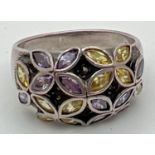 A modern design dome style silver dress ring with stone set flower detail. Ring set with purple