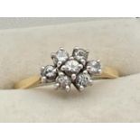 An 18ct gold and diamond ring. with 7 round cut diamonds in a flower shaped setting, totalling .