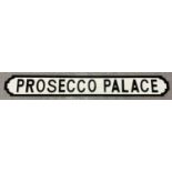 A modern wood 'Prosecco Place' wall sign, painted black & white, in the style of an old street sign.