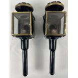 A pair of vintage carriage lamps, painted black with brass trim and red and clear glass lenses. Each