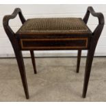 An Edwardian dark wood piano stool with curve design handle sides. Raised on square legs, with
