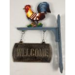 A painted cast iron wall hanging garden welcome sign with cockerel decoration. Approx. 45cm tall.