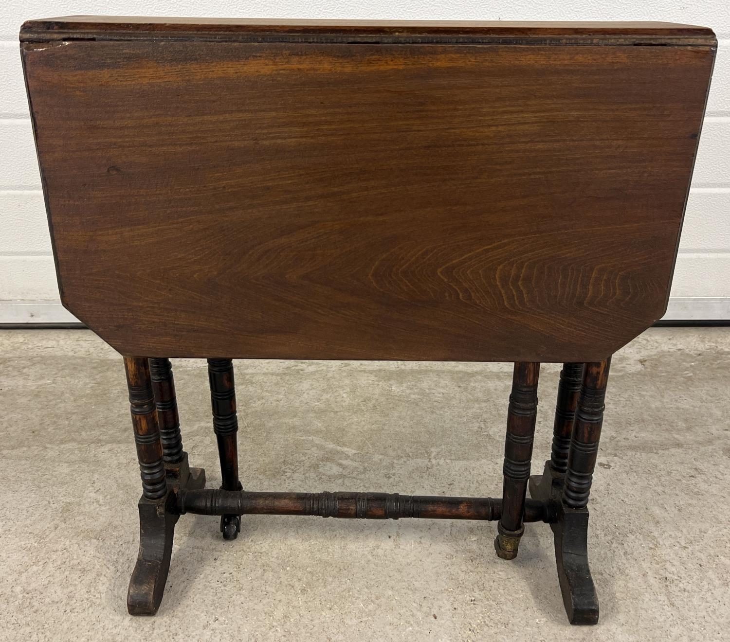 A small antique dark wood Sutherland style drop leaf table with turned detail to legs. Gateleg