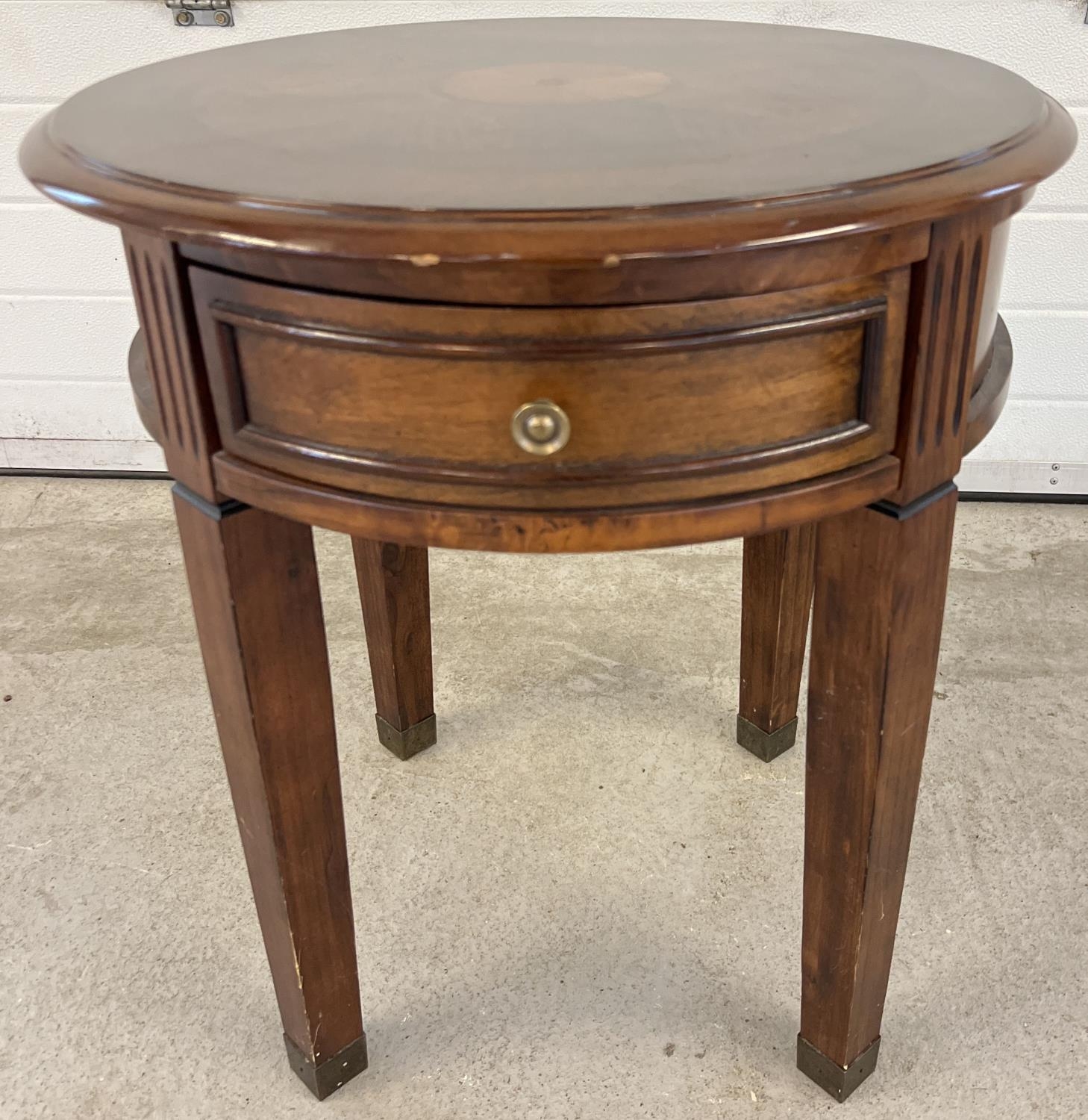 A modern circular shaped drum table raised on 4 squared shaped tapered legs and with central draw.