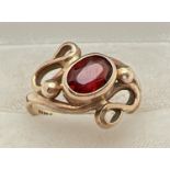 A 9ct gold and garnet contemporary design bespoke ring. Central oval cut garnet bezel set within a