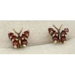 A pair of 9ct gold garnet set butterfly shaped stud style earrings, complete with butterfly backs.