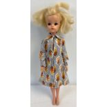 A vintage 1983-1985 Sindy doll with blonde hair, in a brown, orange and yellow print dress.
