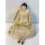 An antique 9.5" porcelain doll with straw filled body in Edwardian dress. Porcelain head, hands