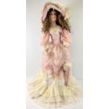 A large life sized soft bodied porcelain doll on a stand, in Victorian style dress with matching