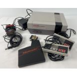 A 1985 Nintendo Entertainment System (NES), with 2 hand held controllers and AC adapter.