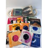 A collection of 60+ vintage 7" single records together with a vintage vinyl record carrier.