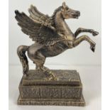 A large bronzed effect cast iron figurine of a rearing flying horse on a rectangular shaped base.