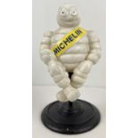 A painted cast iron figure of a seated Michelin man on a rotating circular pedestal base. Approx.