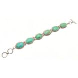 A six oval panel silver bracelet set with blue/green turquoise, with a t bar clasp. Silver marks