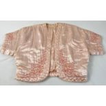 A vintage pink satin quilted bed jacket with embroidered detail.