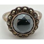 A vintage silver dress ring set with a central round cut hematite stone, surrounded by 14