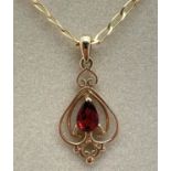 A boxed 9ct gold Art Nouveau style pendant set with a teardrop cut garnet. On an 18" curb chain with