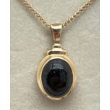 A boxed 9ct gold oval pendant set with a cabochon of black onyx. On an 18" foxtail chain with spring