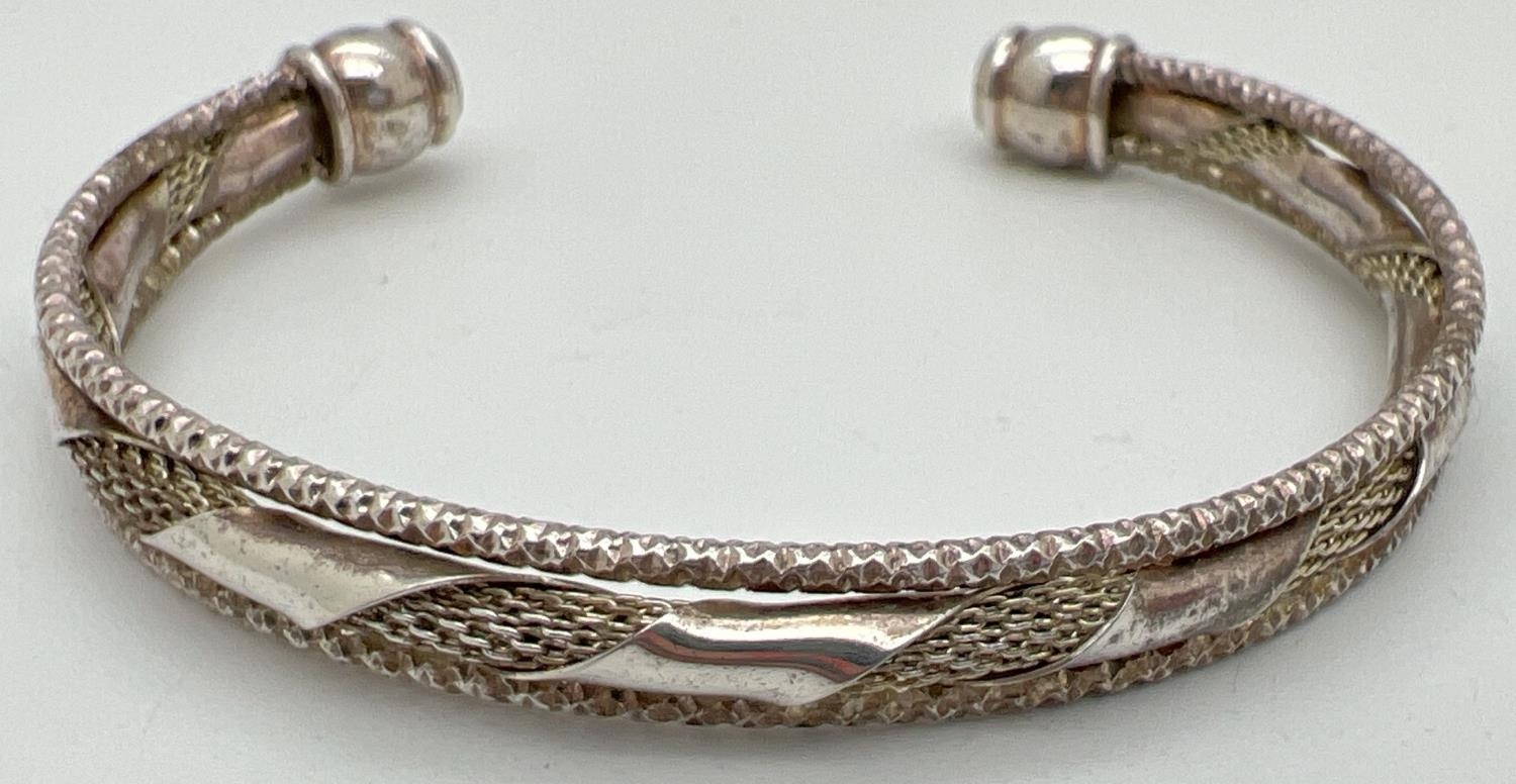 A decorative 3 band cuff bangle with twist design to middle band. Silver marks to one end. Total