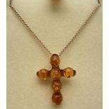 A boxed 9ct gold amber set cross pendant on an 18" curb chain with lobster claw clasp. Pendant set